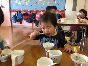 0歳児が大きな口で七草がゆを食べている
